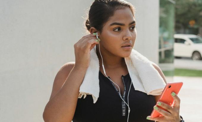 Жена држи телефон са слушалицама